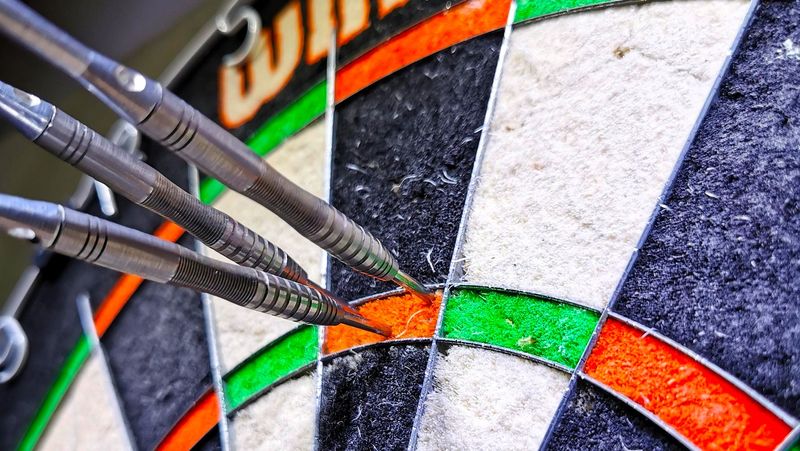 three silver darts in a dart board