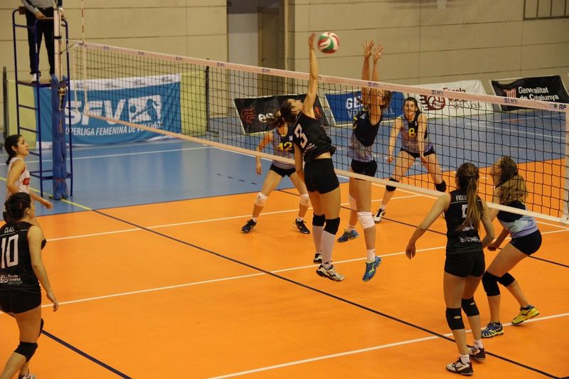 volleyball players spiking the ball in front of the net