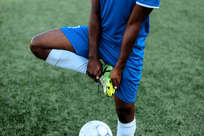 a soccer playing adjusting his soccer cleat