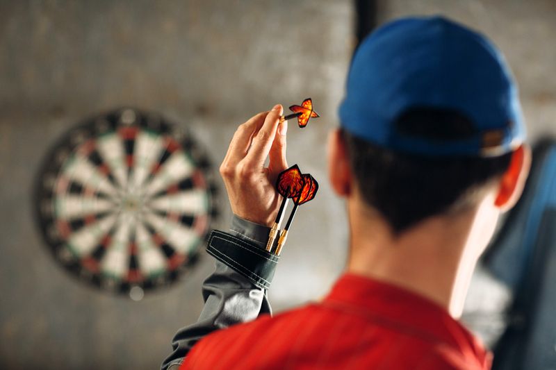 an adult male about to throw a dart at a dart board