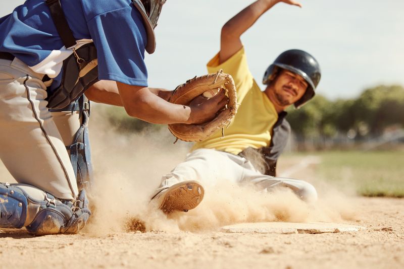 a male baseball player sliding in dirt to a base