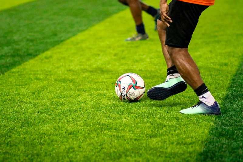 a soccer player on a turf soccer pitch dribbling a soccer ball