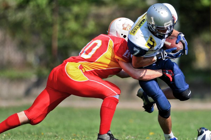 a football player tackling an opposing team player handling the football