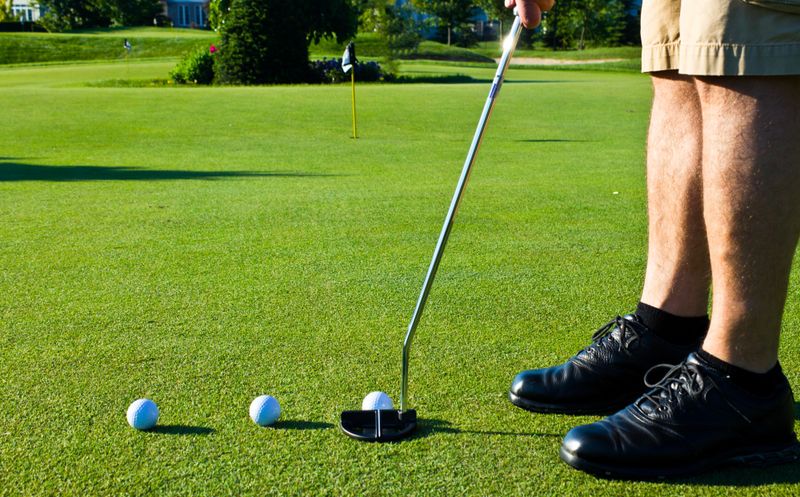 a male adult with three golf balls practicing putting
