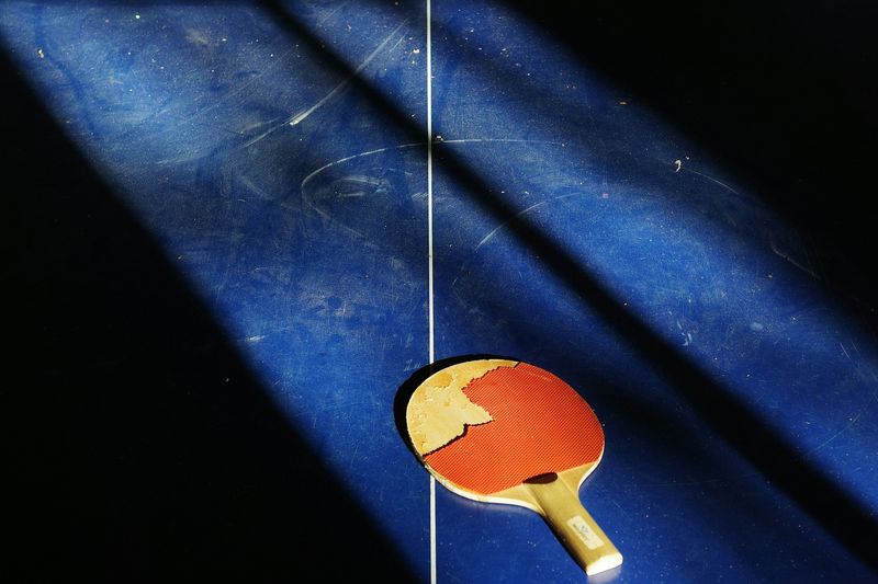 a dusty ping pong table with a pong pong paddle lying on the surface