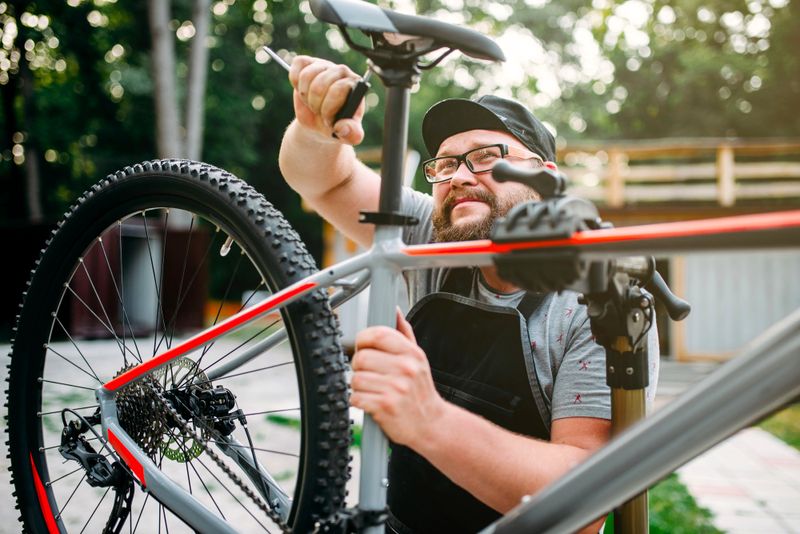 an adult male repairing the seat in his bicycle