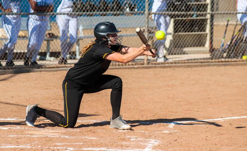 a young female softball player batting a softball