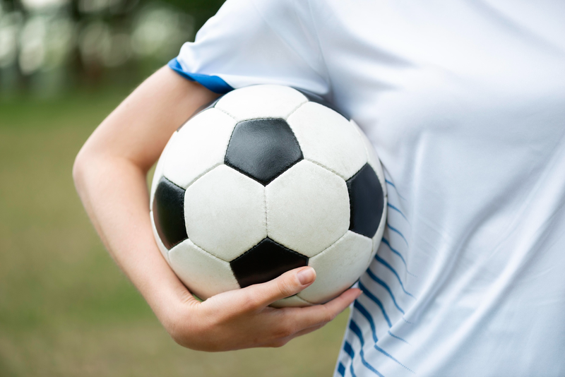 a female soccer player wearing a white jersey holding a black and white soccer ball