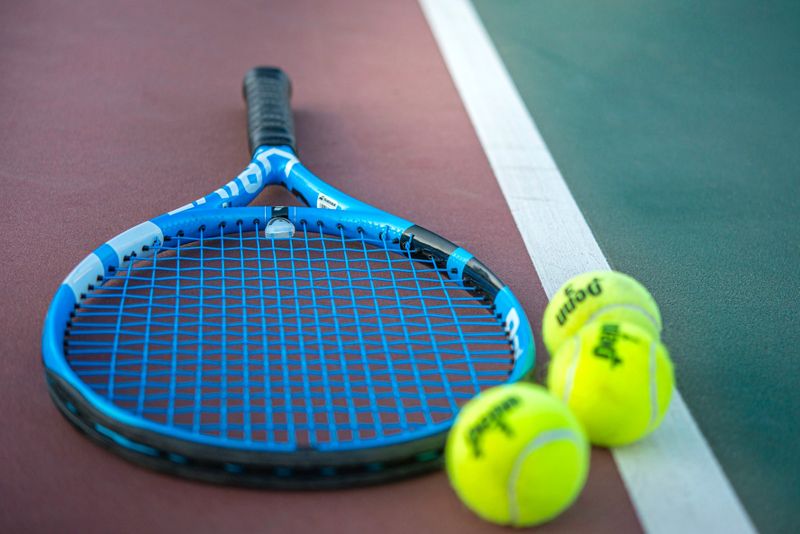 a tennis racket beside three tennis balls