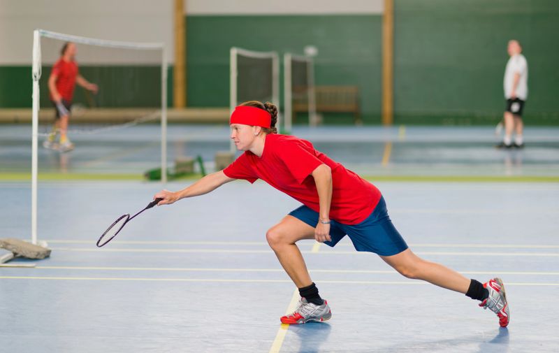 a badminton player reaching to hit a shuttlecock