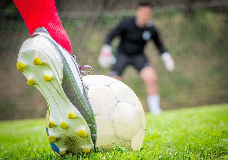 a close up of a soccer cleat about to hit a soccer ball