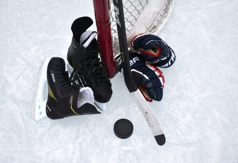 a taped hockey stick with gloves and helmet