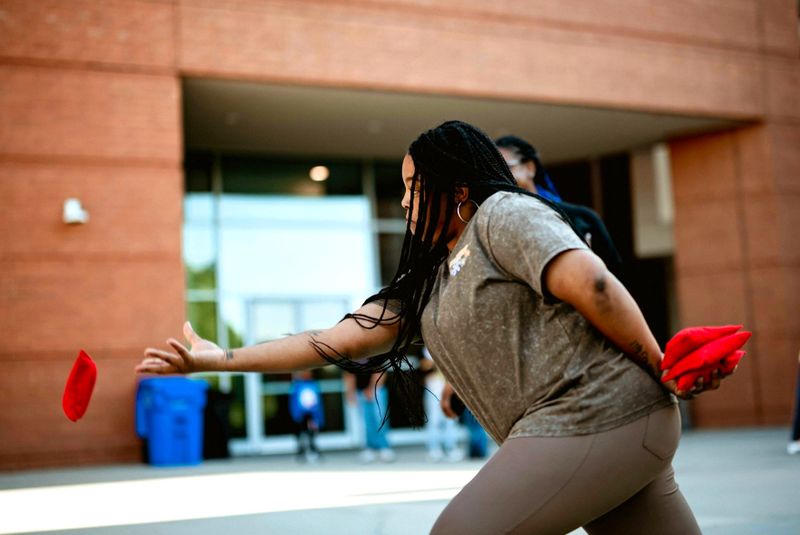 an adult woman throwing a cornhole bag