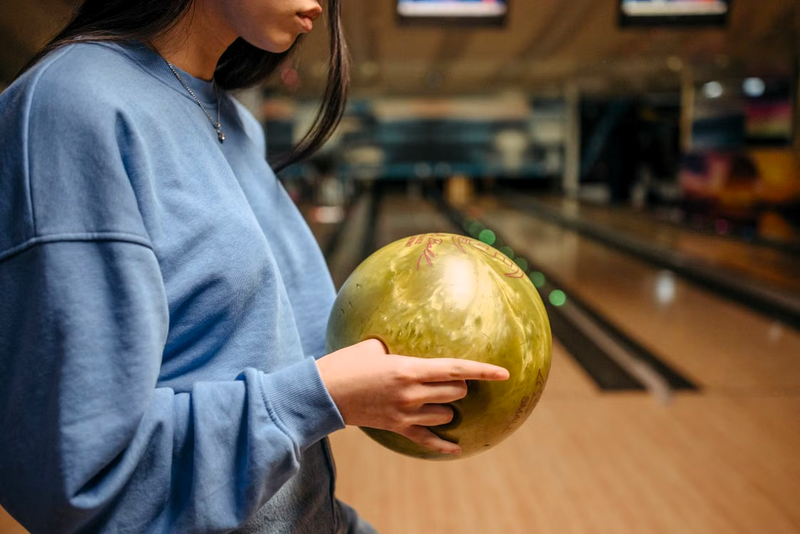 an adult female holding a yellow bowling ball