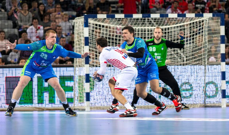 handball players defending against an opponent in front of the goalie
