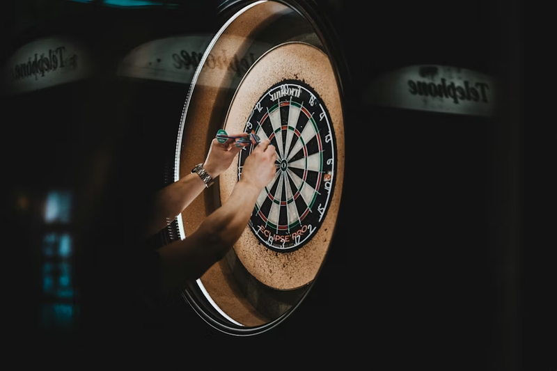 a male adult taking darts out from a dartboard
