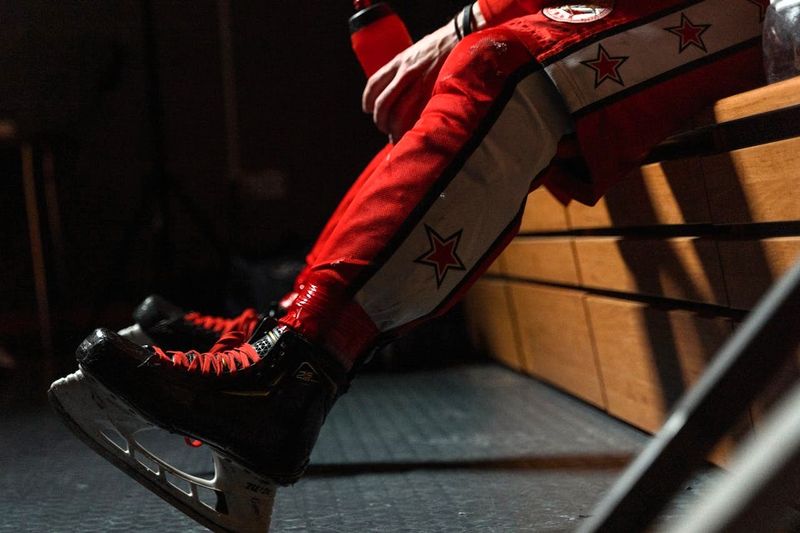 a hockey player sitting on a bench with hockey tape around their socks