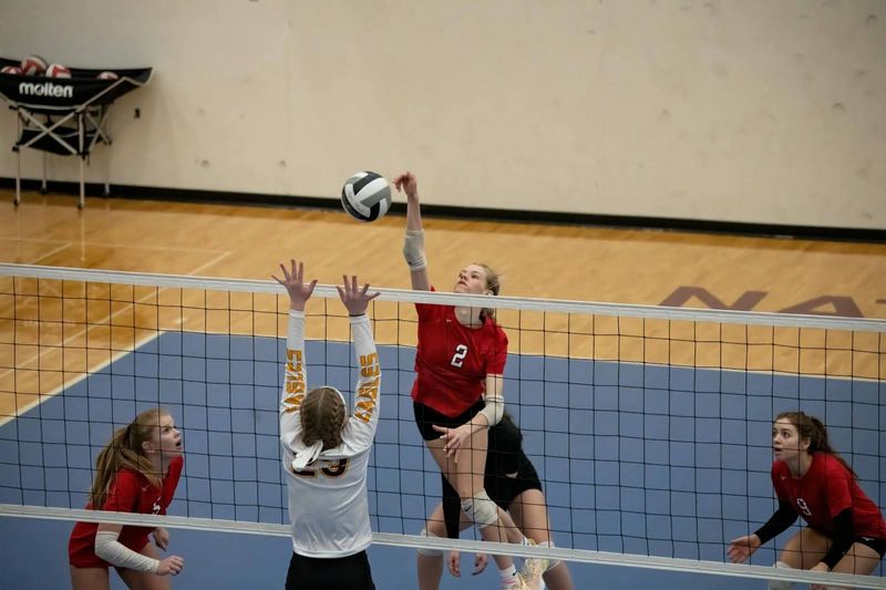 A female volleyball player spiking the ball over the net