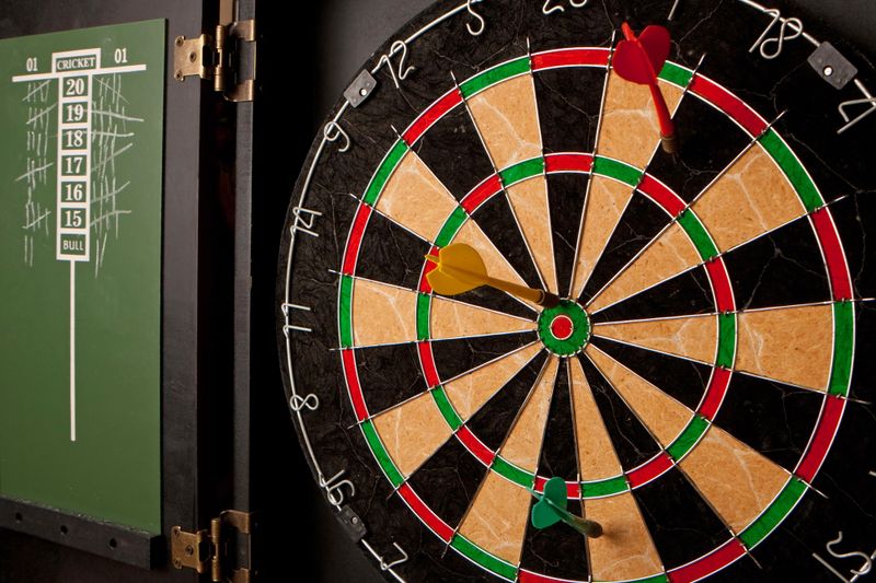 a dart board with a green score board to the left of the dart board