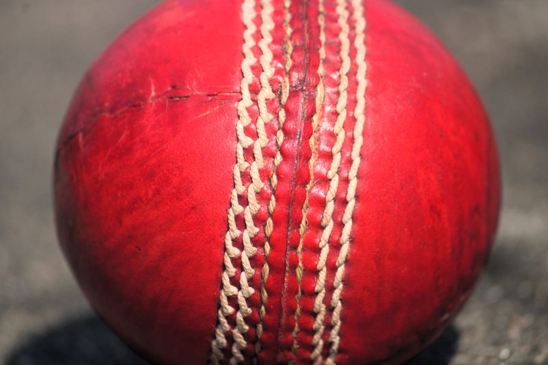 a red cricket ball with a close up on the stitching