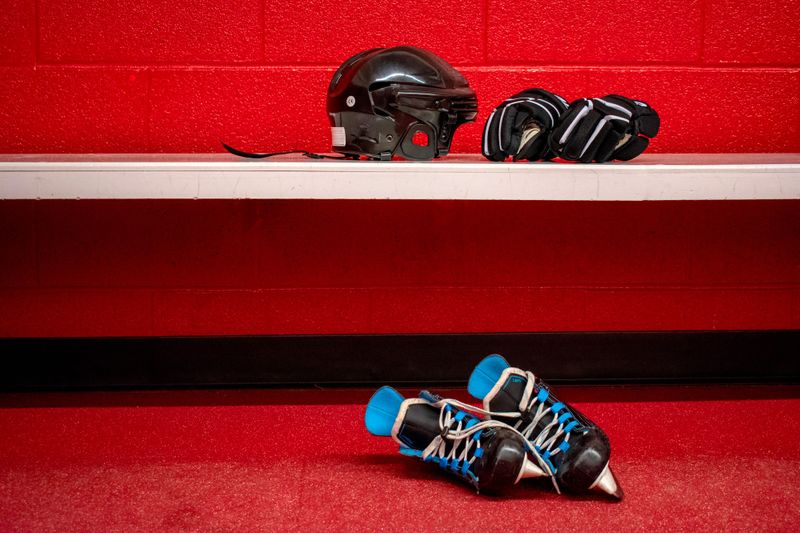 ice hockey gear in a red locker room with a bench