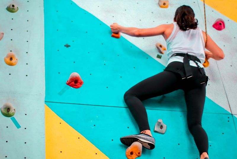 an adult female climbing on an indoor rock climbing wall
