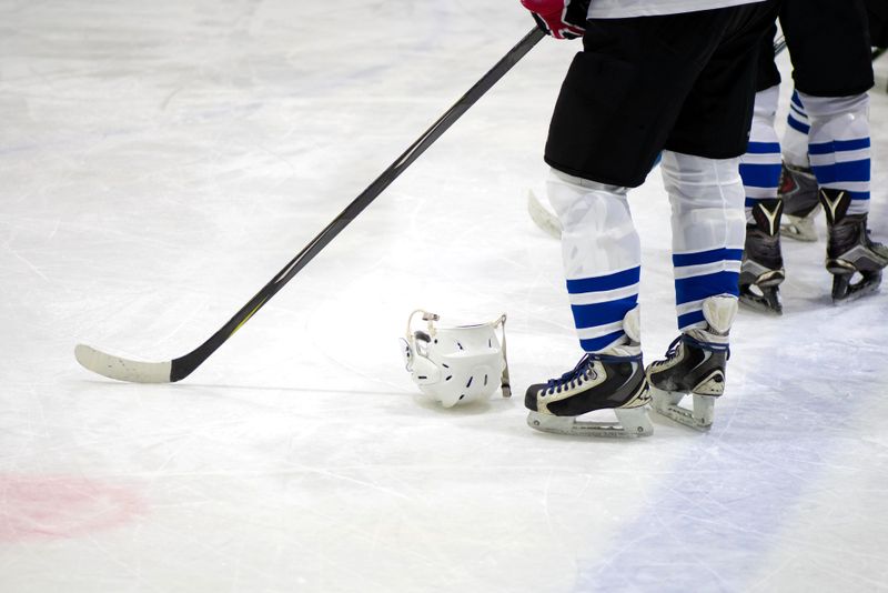 an ice hockey player standing on an ice rink next a helmet on the ice