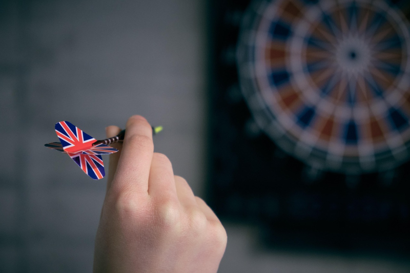 a hand holding a dart with an english flag flight