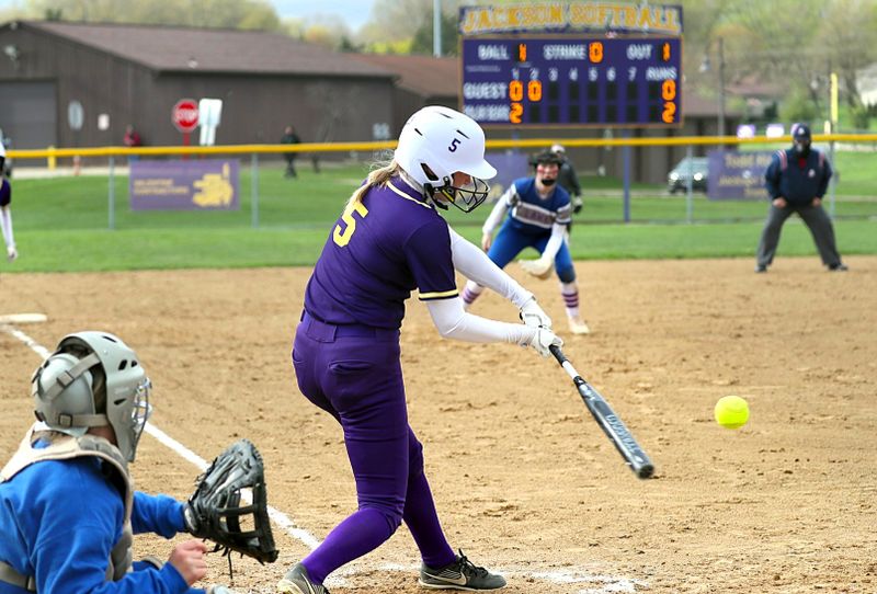 a softball player hitting a softball pitch