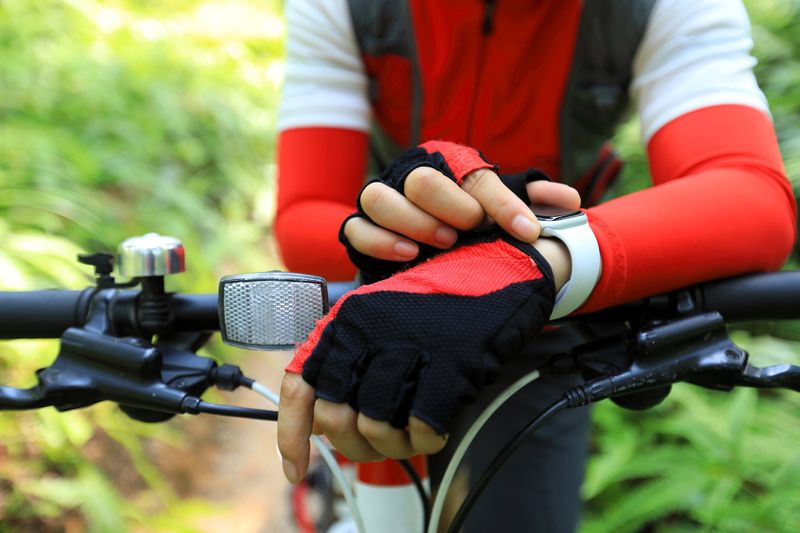 a close up of a cyclist wearing cycling gloves checking their watch