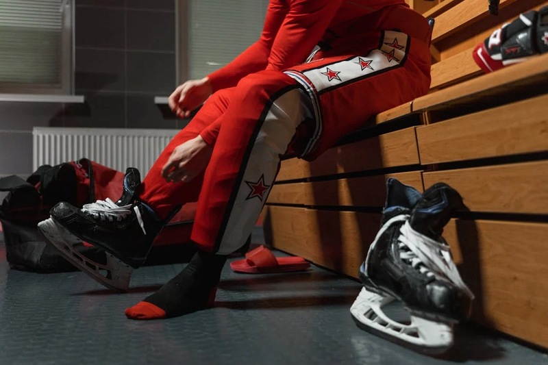 an ice hockey player putting on hockey gear in a locker room