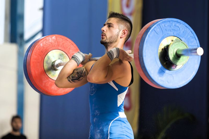 a male powerlifting doing a clean and press