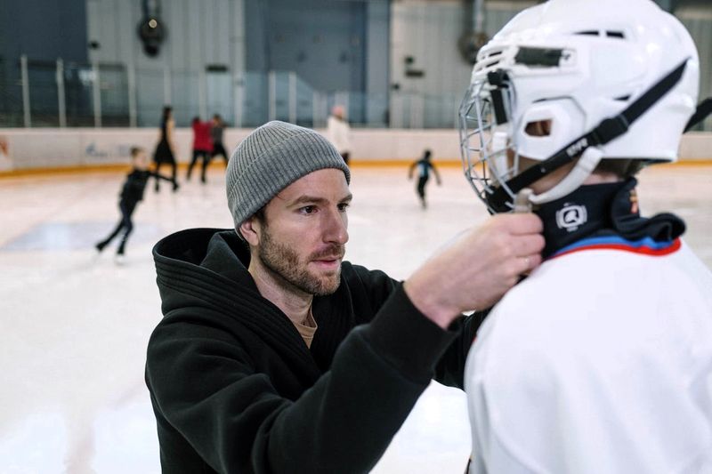 coach helping youth a hockey player with helmet