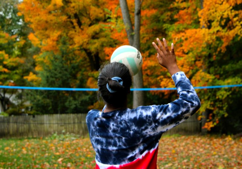 a young female practicing volleyball in a home backyard
