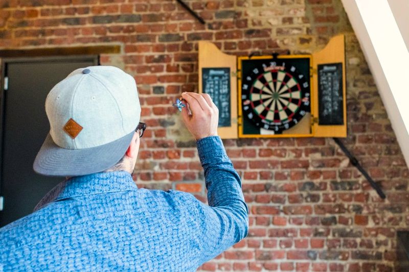 a male adult throwing a dart at a dart board