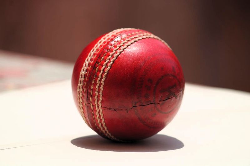 a close up of a red cricket ball on a table
