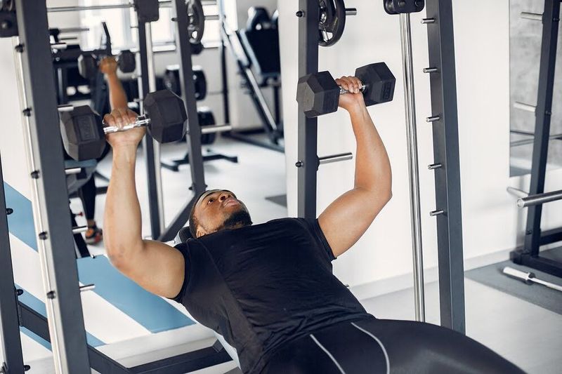 adult male doing bench press exercise