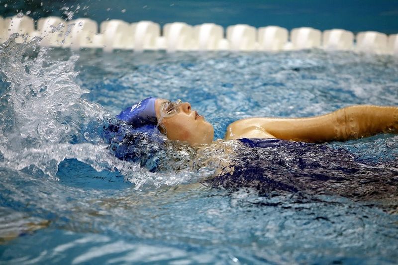 a female swimmer backstroke swimming in a pool