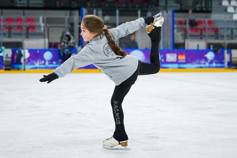 a young female figure skater skating on an ice rink