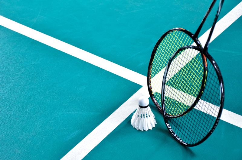 two badminton rackets and shuttlecock on a court