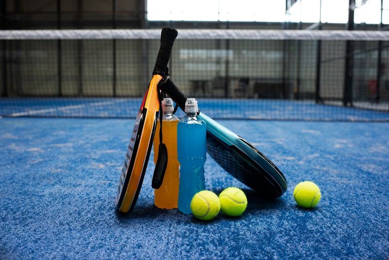 two padel rackets and padel balls on a blue padel court