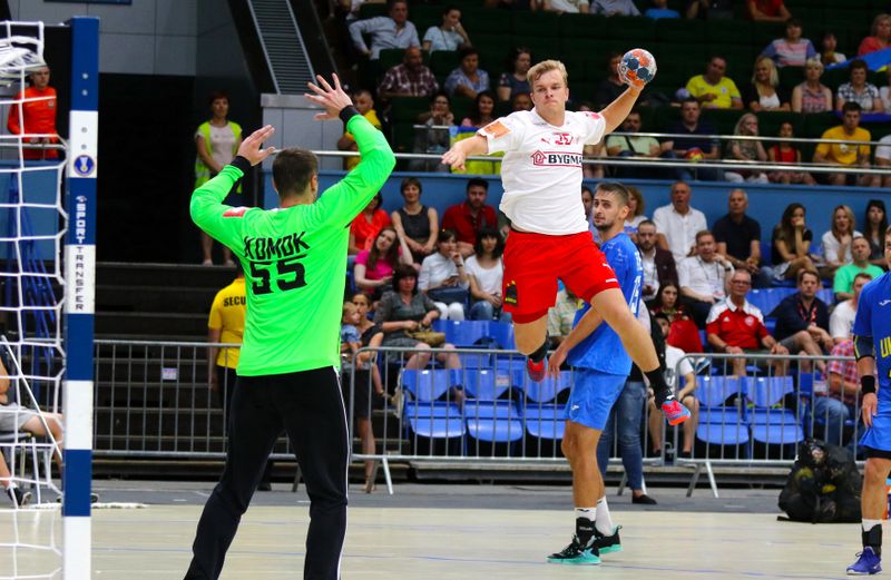 a handball player taking at a jump shot at the goal