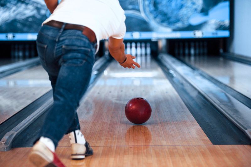a make adult releasing a bowling bowl down a bowling lane