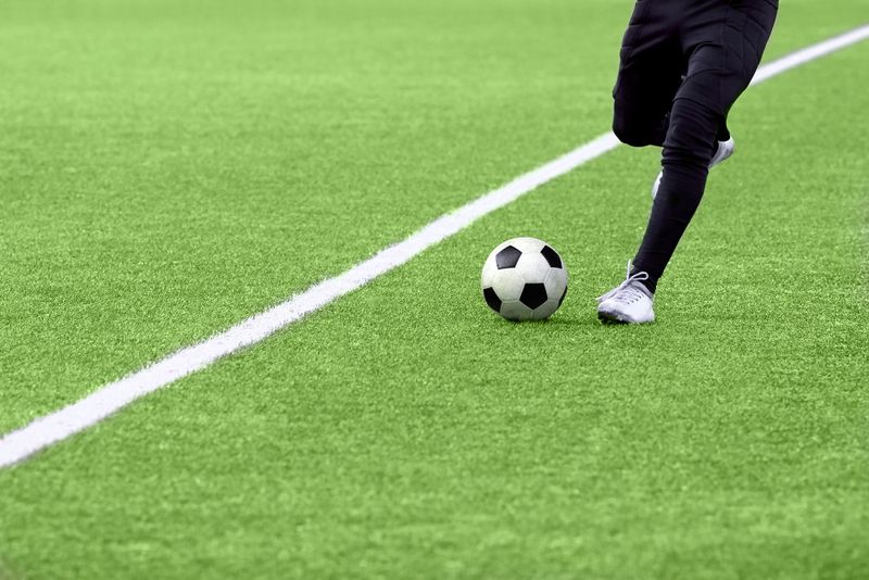 a soccer player about to kick a ball on a turf soccer pitch