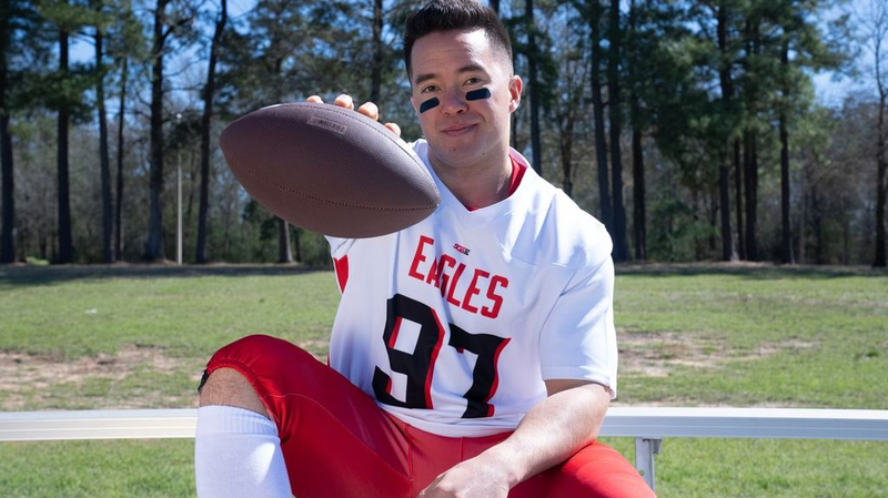 an adult male football player wearing a red and white football uniform holding a football
