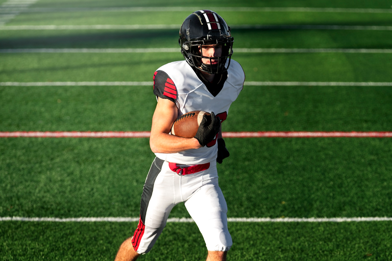 a male football player in a white and red uniform carrying a football