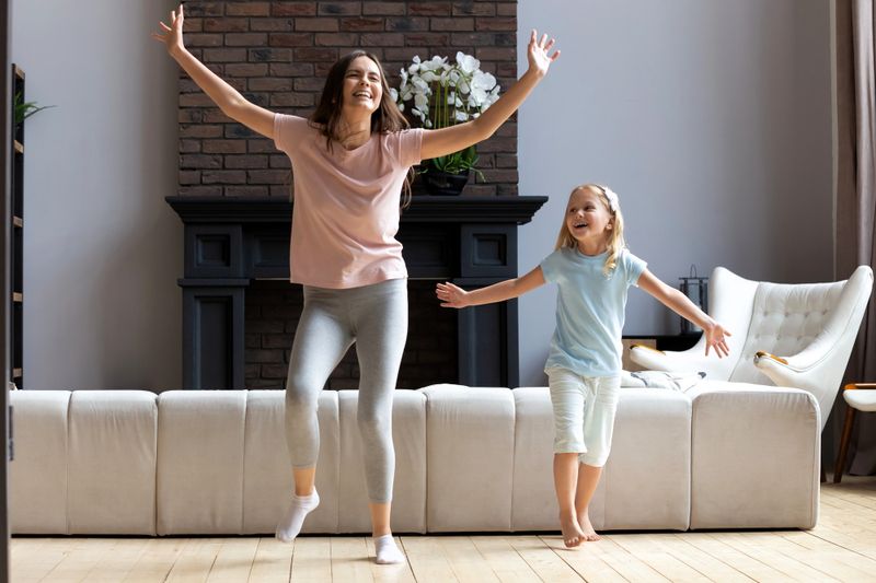 a mother and young child dancing in their living room
