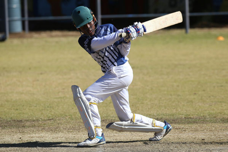a young male cricket player swinging a cricket bat