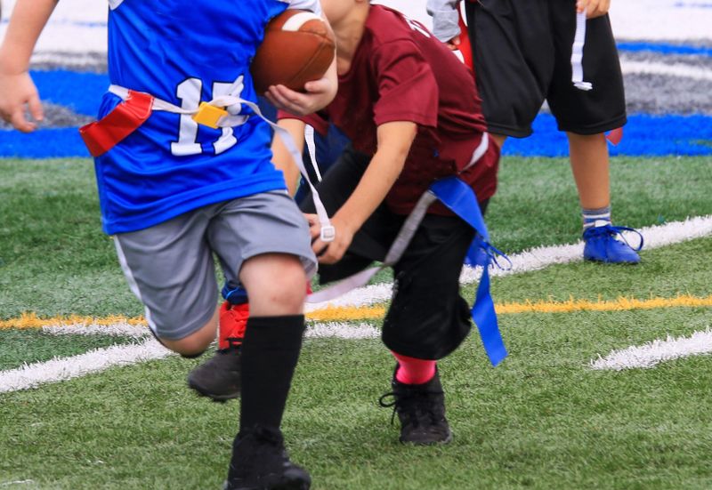 a flag football player grabbing a flag from an opponent