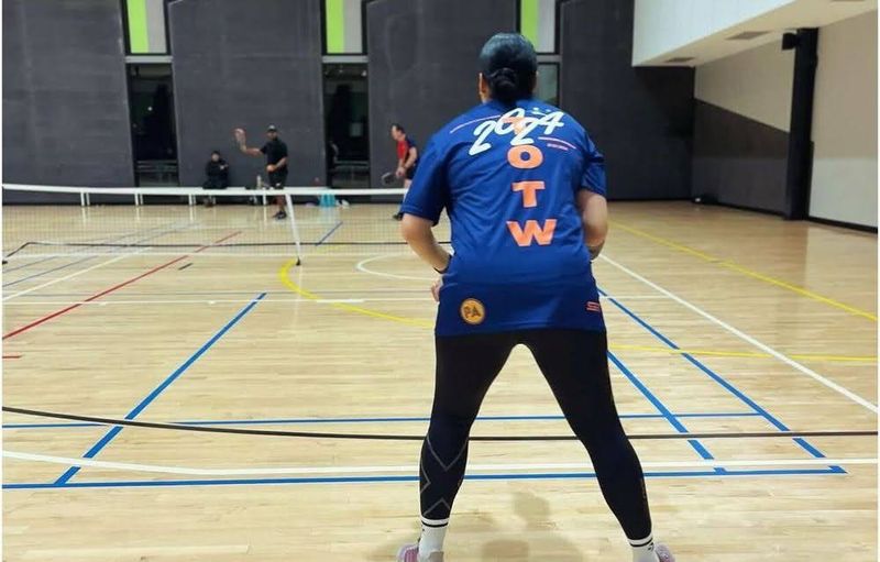 woman playing pickleball wearing black leggings